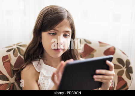 Girl using digital tablet on sofa Stock Photo