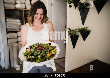 Woman serving large dish of salad at retreat Stock Photo