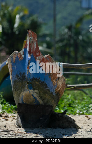 Lombok, Indonesia. A small blue and red boat sits near the beach on the island of Lombok. Stock Photo