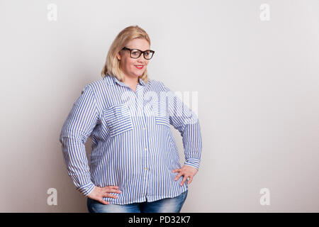 Portrait of an attractive overweight woman with glasses in studio. Stock Photo