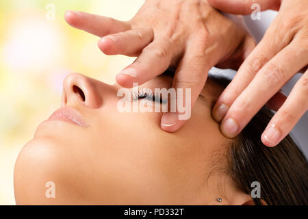 Extreme close up portrait of woman having beauty facial treatment. Therapist doing massage with product on cheek. Stock Photo