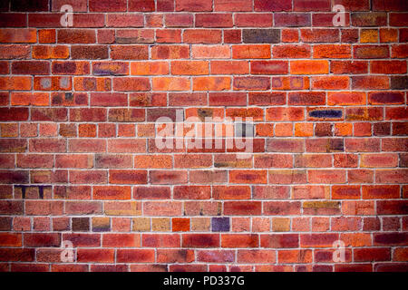 Close-up of a ​multicolored, warm color wall with red, orange and black brick.  Brick wallpaper, background. Stock Photo