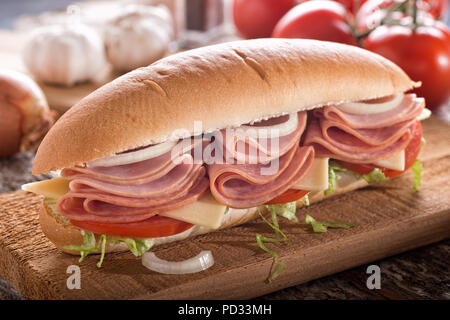 A delicious submarine sandwich with deli meats, lettuce, tomato, onion and cheese on a sub bun. Stock Photo