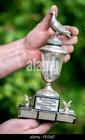 Arnum, Germany. 11th May, 2018. A pigeon breeder of the Reisevereinigung Leinetal (lit. travel association Leine valley) holds the challenge cup of the 1965 award flight season in his hands. Around 3900 pigeon breeders are active in Lower Saxony. The breeders have organised themselves in eight regional associations and regularly organise prize flights. Credit: Hauke-Christian Dittrich/dpa/Alamy Live News Stock Photo