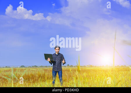 Man holding computer in green field under blue sky.Blogger Sky and Clouds Stock Photo