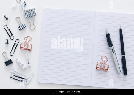 White office desk table with open notebook with empty pages and other office supplies. Top view Stock Photo