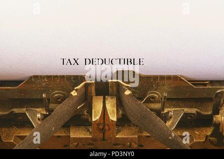 Closeup on vintage typewriter. Front focus on letters making TAX DEDUCTIBLE  text. Business concept image with retro office tool Stock Photo