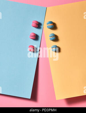 On a multi-colored cardboard pink and blue macaroons on a pink background background. Top view Stock Photo