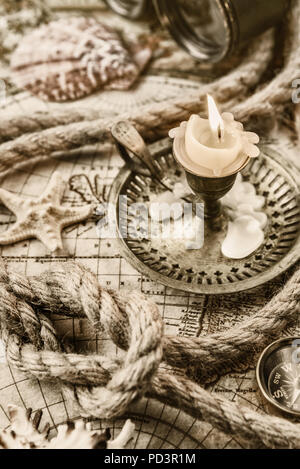 Burning candle, compass, starfish, binoculars and the ship's rope located on the background of old map Stock Photo