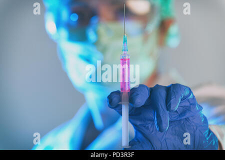 Scientist working in a laboratory holds a syringe in her hand