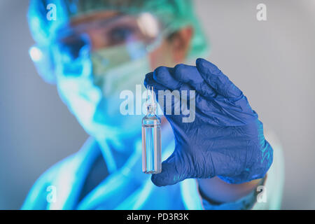 Scientist working in a laboratory holds an ampoule with a new vaccine in her hand Stock Photo