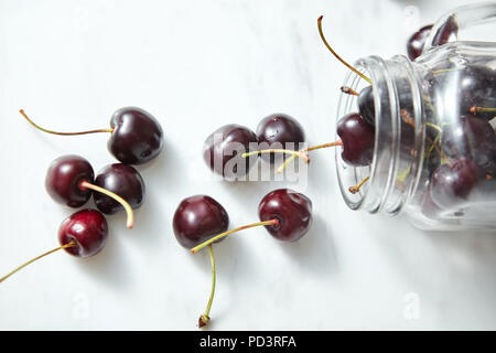 Organic freshly picked red cheries in a glass jar on a kitcen table. Natural ingredients for cooking sweet jam. Stock Photo