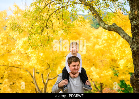 Father giving his son piggyback ride in autumn park, Adelaide Hills, South Australia Stock Photo