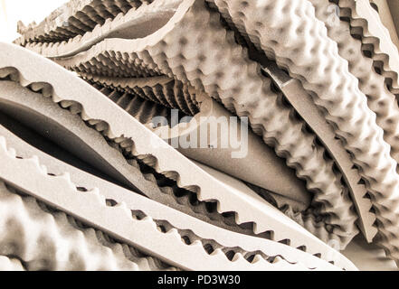 Beige egg-crate pressure relieving foam mattress pads, overlays and toppers bundled up in a pile showing surface dimples, hollows, peaks and troughs. Stock Photo