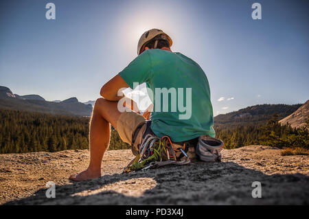 Young male climber sitting on top of rock formation, Tuolumne Meadows, upper part of the Yosemite National Park, California, USA Stock Photo