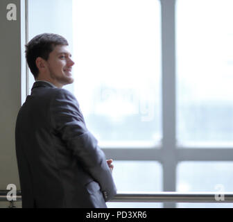 smiling businessman standing near a large office window Stock Photo