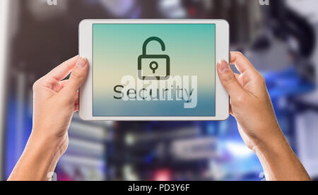 Security written on tablet screen with hands holding the device up with server room in the background Stock Photo