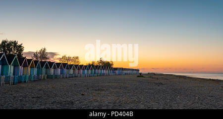 Attractive Beach huts at sunrise in summer on deserted West Mersey seaside resort beach in England Stock Photo