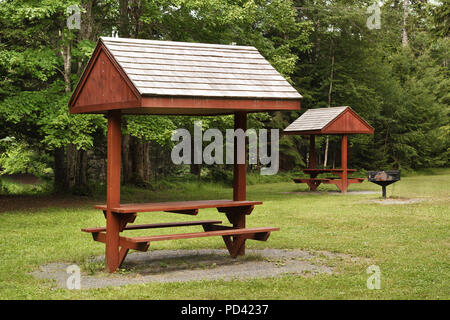 Barbecue and roof covered picnic table in rural park setting. Stock Photo