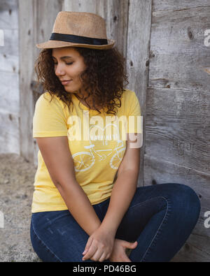 Close up portrait of a curly young woman sitting outdoors.