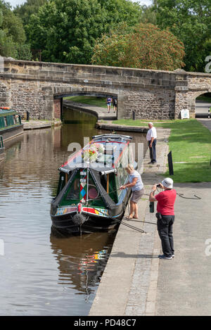 Man and woman tying up boat on jetty, fishing boats moored 