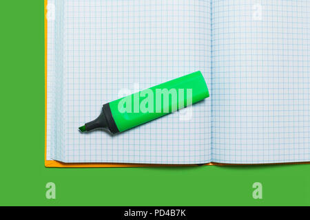 opened workbook and a marker on a green surface Stock Photo