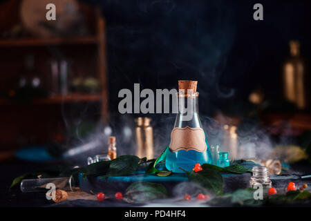 Blank label on a magic potion bottle. Modern witchcraft concept with potions, berries, herbs and occult equipment. Magical still life with copy space on a dark background. Stock Photo