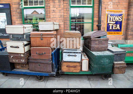 Vintage passenger luggage and suitcases on an old railway platform trolley on the Great Central Railway heritage line. Stock Photo