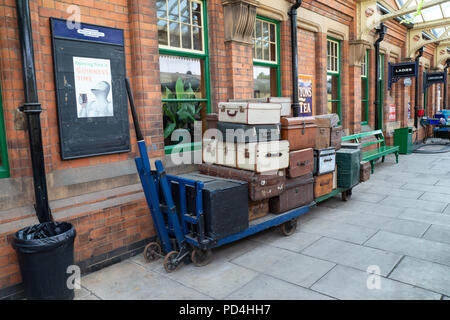 Vintage passenger luggage and suitcases on an old railway platform trolley on the Great Central Railway heritage line. Stock Photo