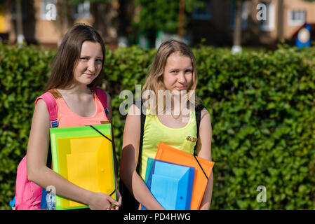 Two girls schoolgirl. Summer in nature. He holds notebooks and textbooks in his hands. Concept Soon to school, preparation for school. Emotion smiles happily. Free space for text. Stock Photo