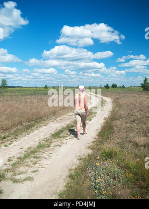 girl walking on the road in the field Stock Photo