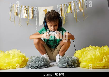 Happy kid playing video games and sitting Stock Photo