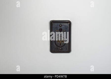 Old fashioned bakelite power socket with on/off switch on a white plaster wall Stock Photo