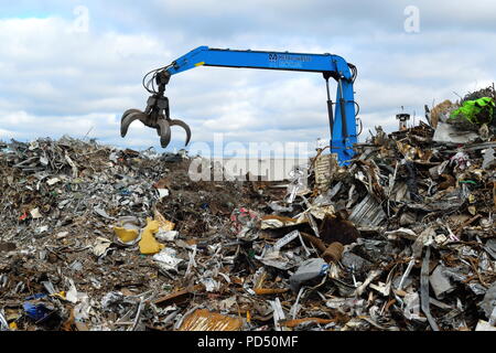 Excavating machine with large grapple claw on the scrap metal recycling site in Edmonton industrial estate, London. Stock Photo