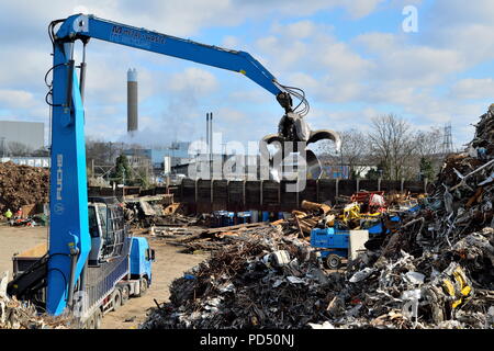 Excavating machine with large grapple claw on the scrap metal recycling site in Edmonton industrial estate, London. Stock Photo