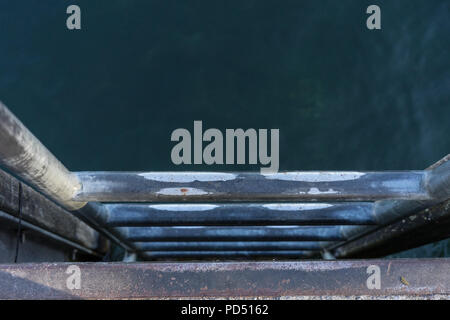 metal stairs leading in to blue water swimming entrance Stock Photo