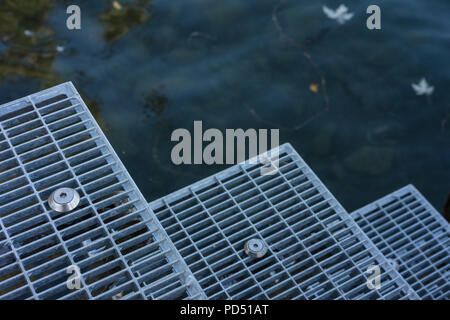 metal stairs leading in to blue water swimming entrance Stock Photo