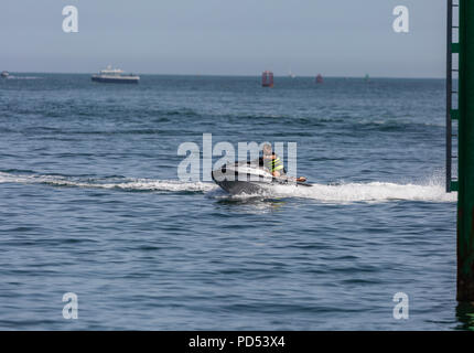 People out enjoying the very hot weather, riding the waves, boating and windsurfing.  Resting and playing on the sand, at Shell Bay and Sandbanks. Stock Photo