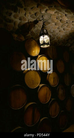 Lamp shining down in a pile of barrels inside a distillery rackhouse Stock Photo