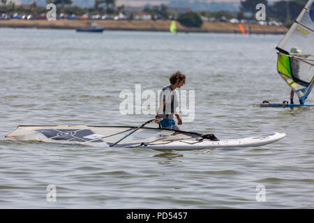 People out enjoying the very hot weather, riding the waves, boating and windsurfing.  Resting and playing on the sand, at Shell Bay and Sandbanks. Stock Photo
