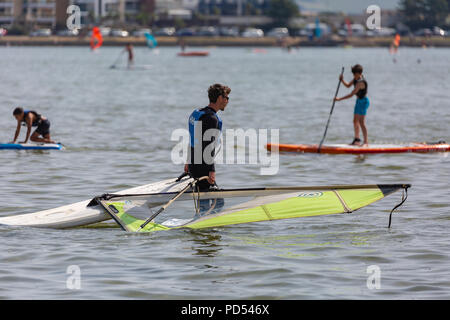 People out enjoying the very hot weather, riding the waves, boating and windsurfing.  Resting and playing on the sand, at Shell Bay and Sandbanks. Stock Photo