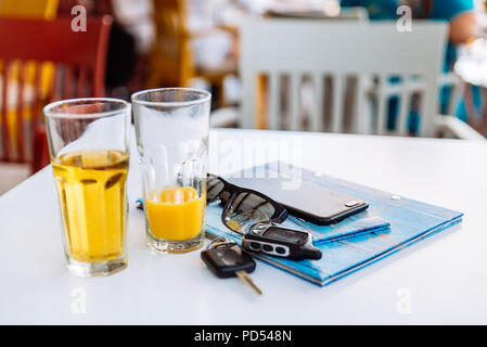 two glass of cool drinks on cafe table with phone menu and car keys Stock Photo