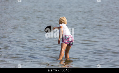 People out enjoying the very hot weather, riding the waves, boating and windsurfing.  Resting and playing on the sand, at Shell Bay and Sandbanks. Stock Photo
