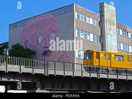 Yellow U-Bahn train and large street art mural at Oberbaum bridge, Berlin-Kreuzberg, Germany Stock Photo