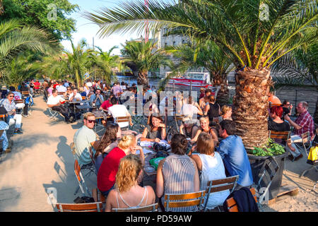 Palm-lined beach bar crowd on the Spree riverside, Spreeuferpromenade, Berlin, Germany Stock Photo