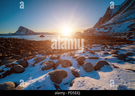 Landscape with beautiful winter sunset and snowy boulders at Lofoten Islands in Northern Norway. Stock Photo