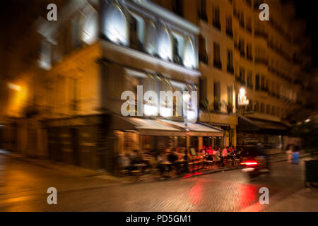 Blurry motion image of people at cafe at night in Paris. Stock Photo
