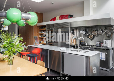 Sleek modern kitchen with stainless steel work units and large green light designed by Andy Martin Stock Photo