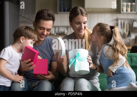 Happy excited parents opening gift boxes with presents from kids Stock Photo