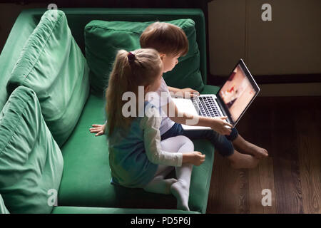 Siblings boy and girl watching kid cartoons using laptop togethe Stock Photo
